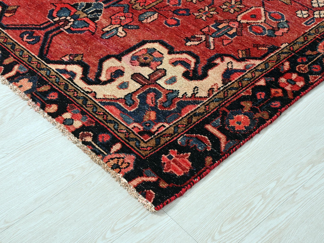 a red oriental rug on a white wooden floor