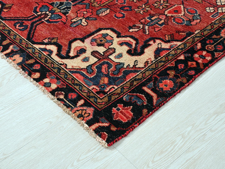 a red oriental rug on a white wooden floor