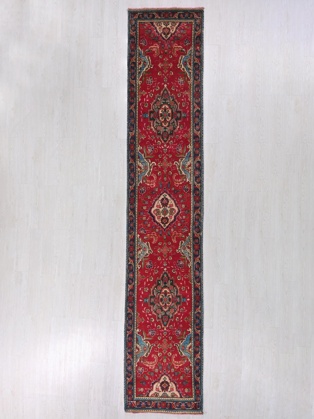 a red rug hanging on a white wall