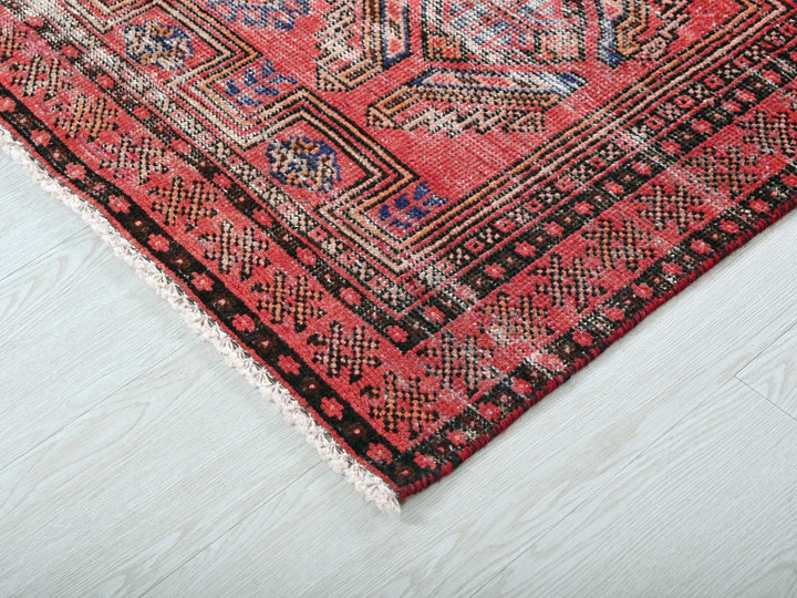 a red rug with a black border on a white floor
