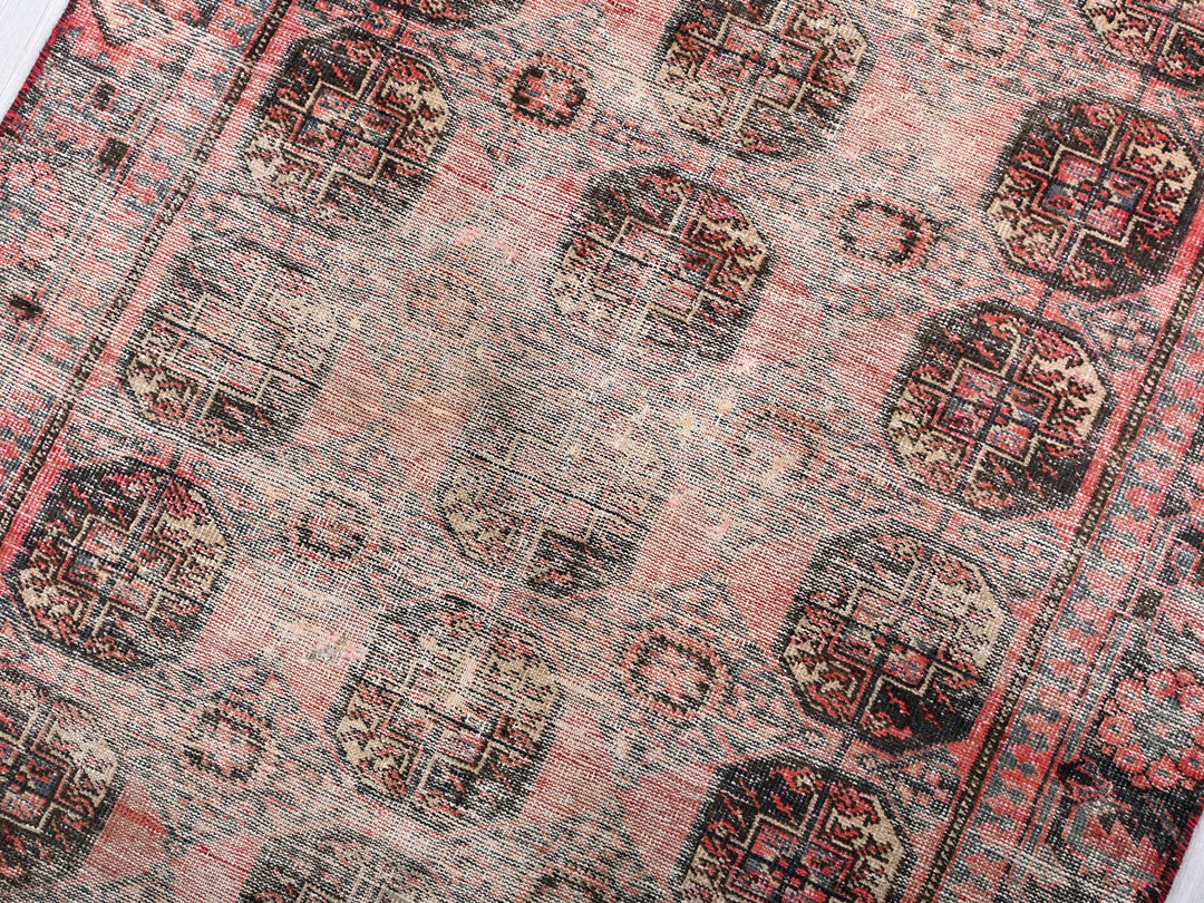 a red and black oriental rug on a white surface