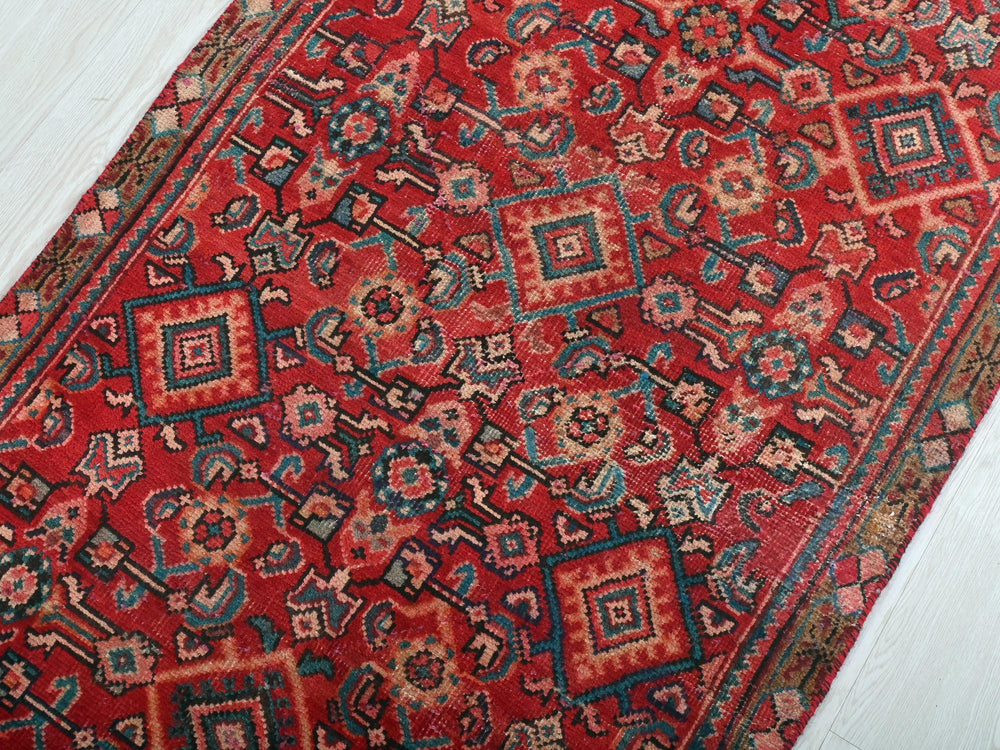 a red oriental rug on a white wooden floor