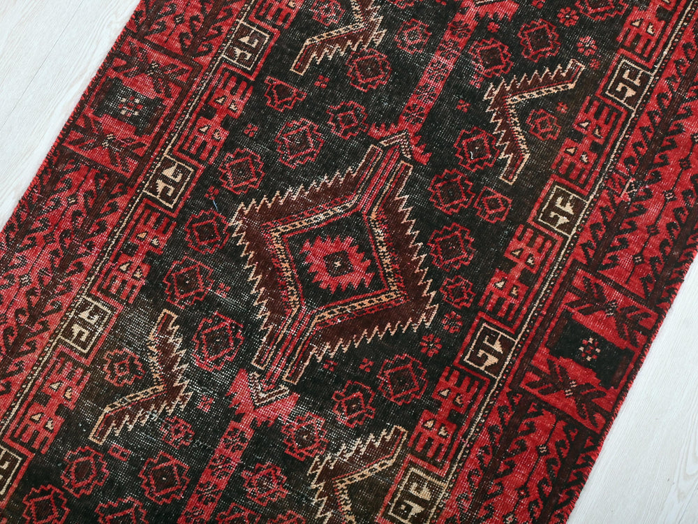 a red and black rug on a white floor