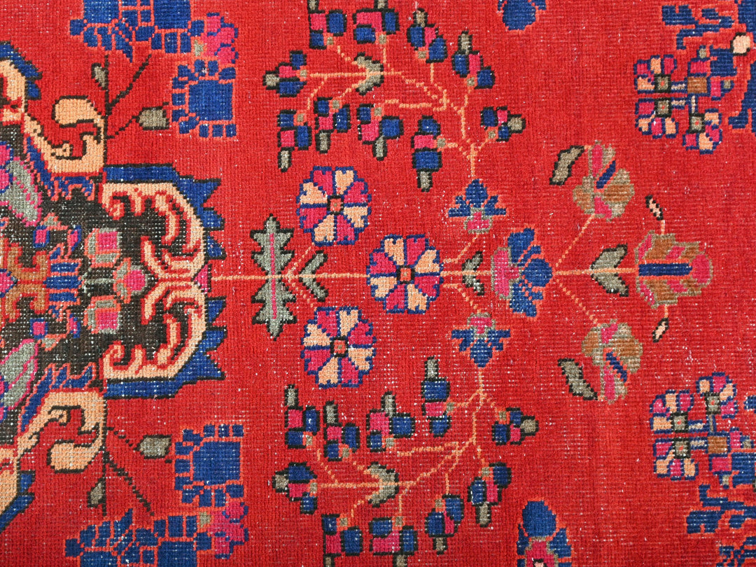 a close up of a red rug with blue and pink designs