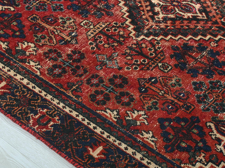 a red rug with a black border on a white floor