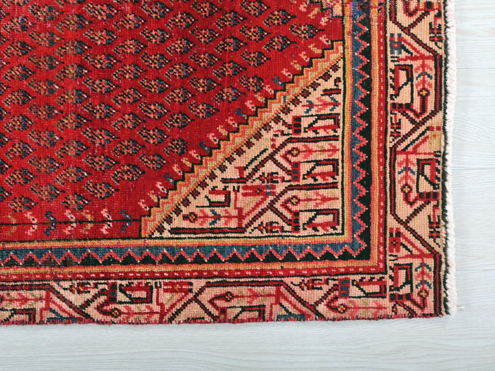 a red rug with a blue border on a white surface