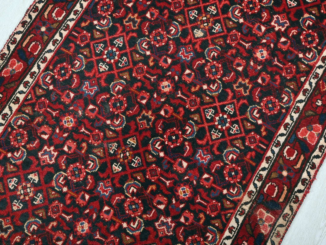 a red and black oriental rug on a white floor