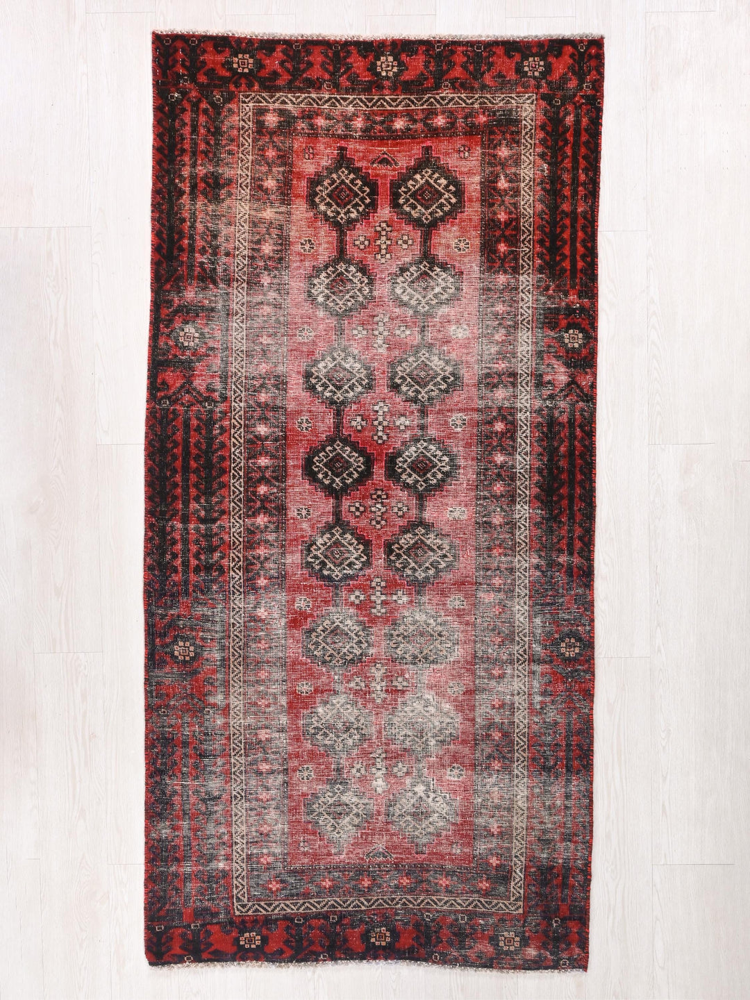 a red and black oriental rug on a white floor