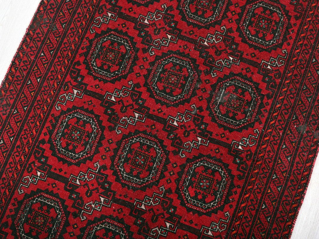 a red and black oriental rug on a white floor