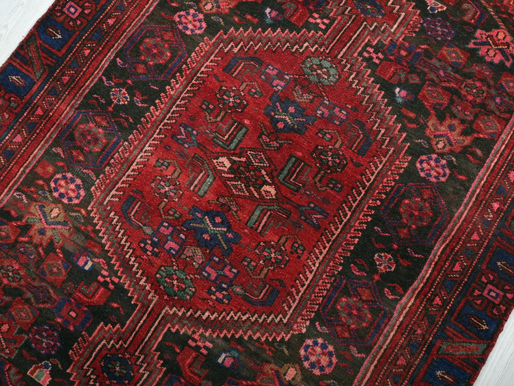 a red and black oriental rug on a white floor