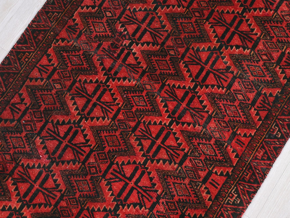 a red and black rug on a wooden floor