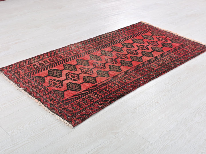 a red and black rug sitting on top of a white floor
