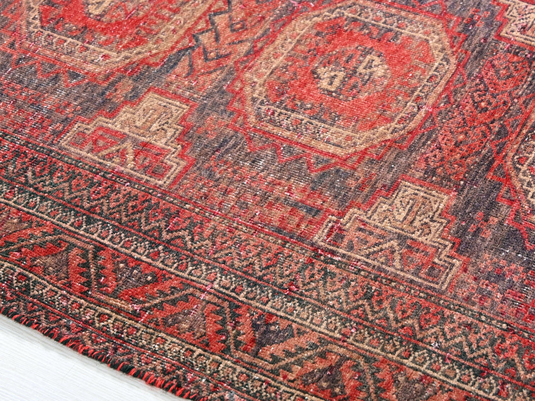 a red and black oriental rug on a white floor