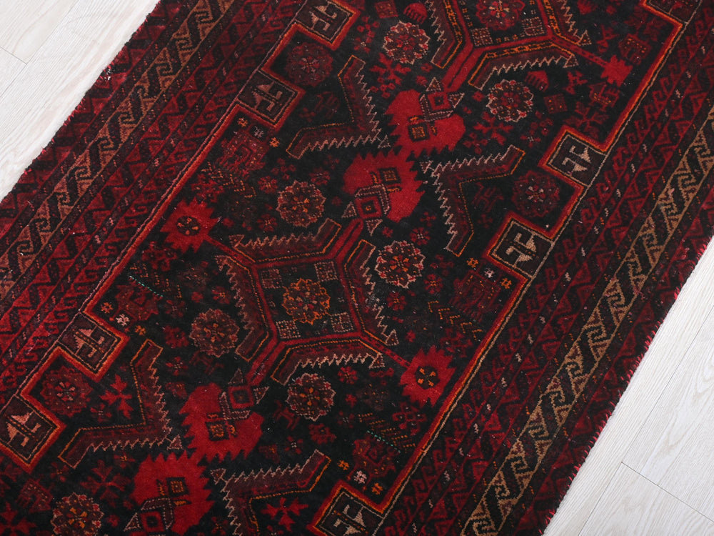a red and black rug on a white floor