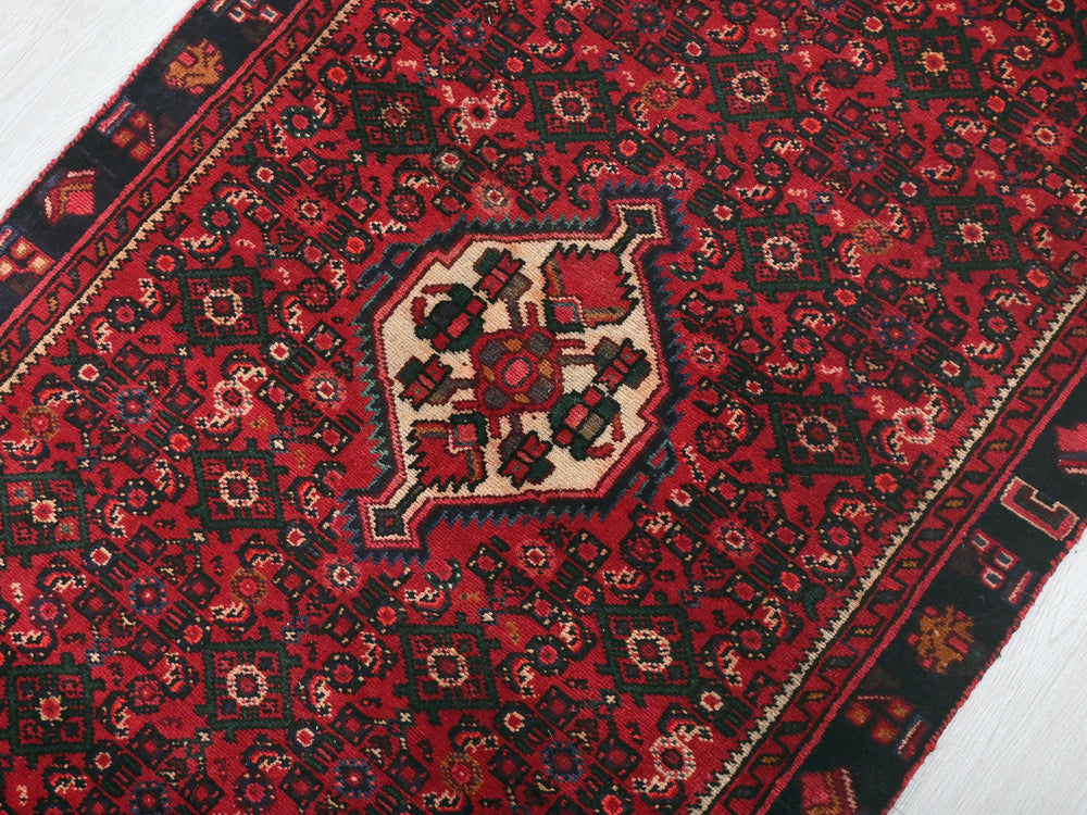 a red and black oriental rug on a wooden floor