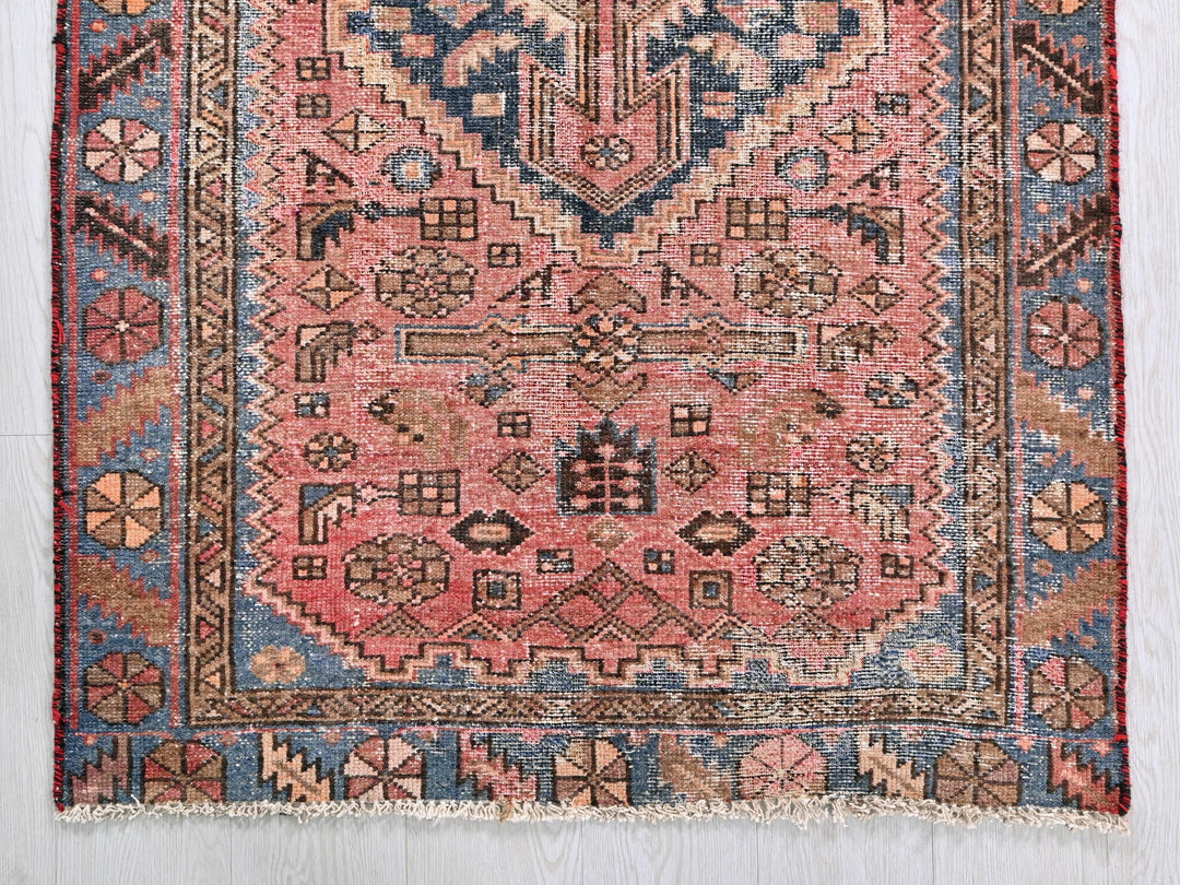 a pink rug with a blue and red design on it