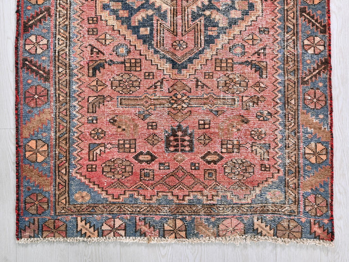 a pink rug with a blue and red design on it