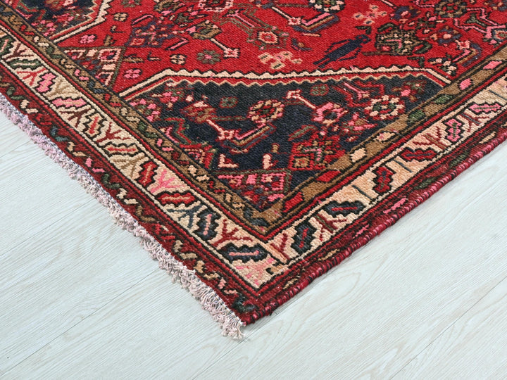a red oriental rug on a white wooden floor