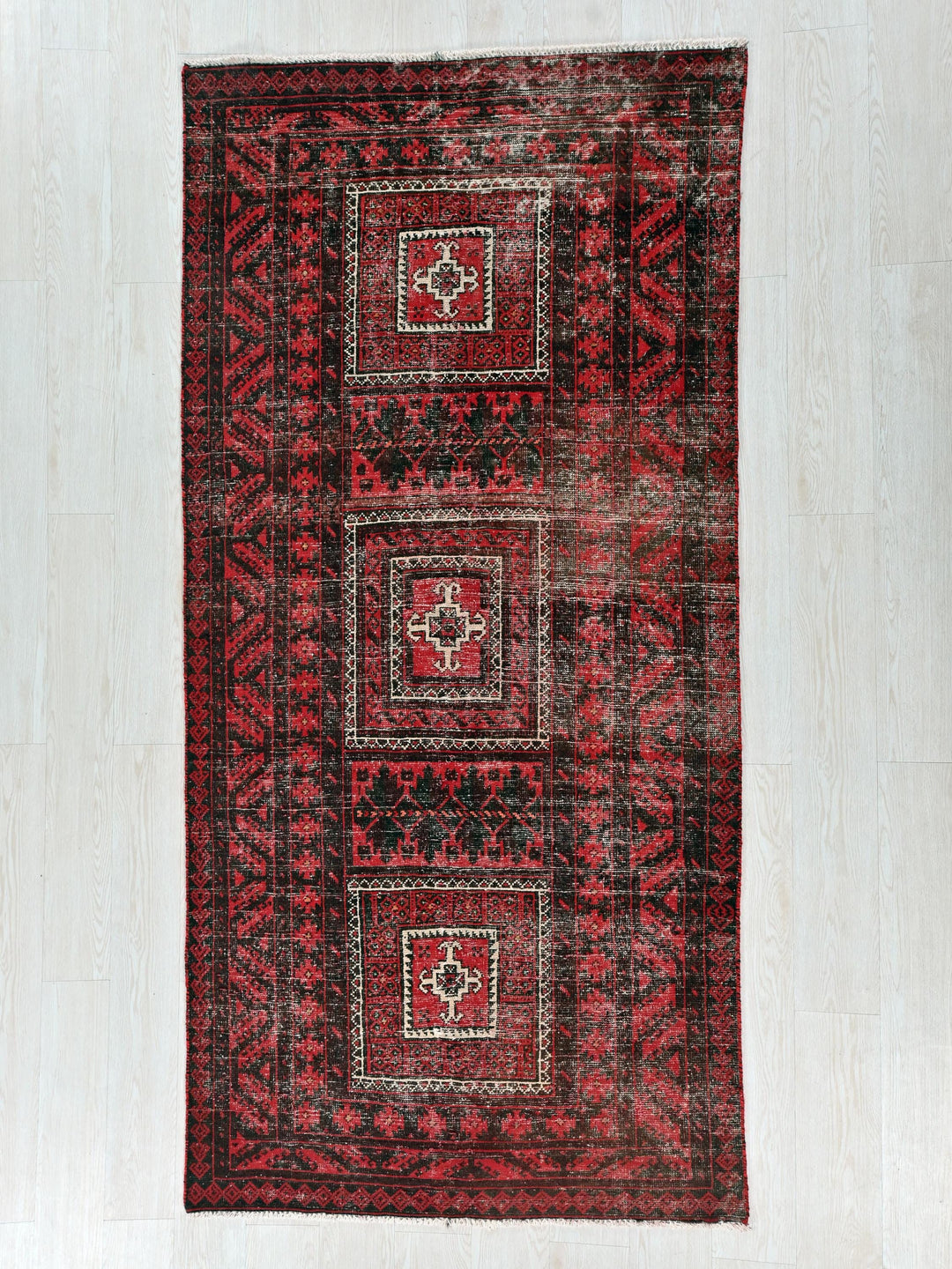 a red and black rug on a white floor