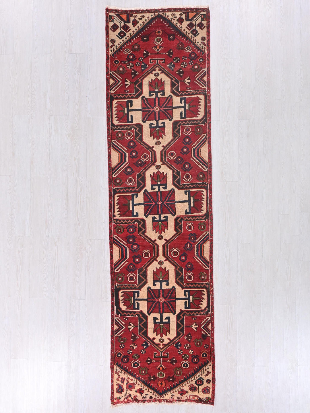 a red and beige rug hanging on a wall