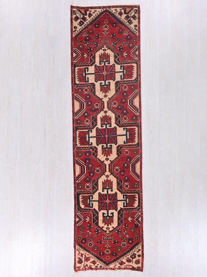 a red and beige rug hanging on a wall