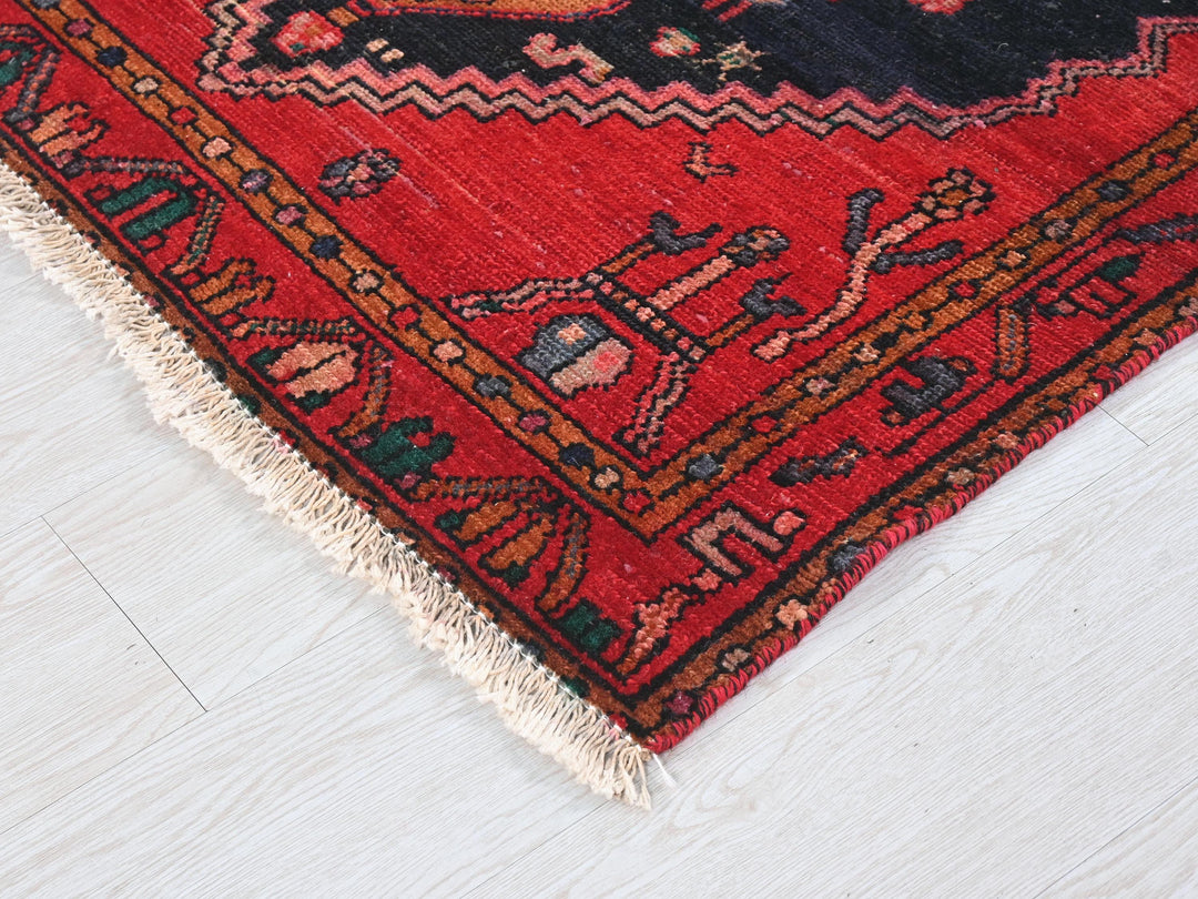 a red oriental rug on a white wooden floor