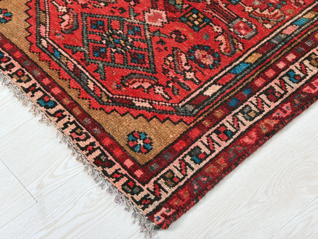 a red oriental rug on a white wooden floor
