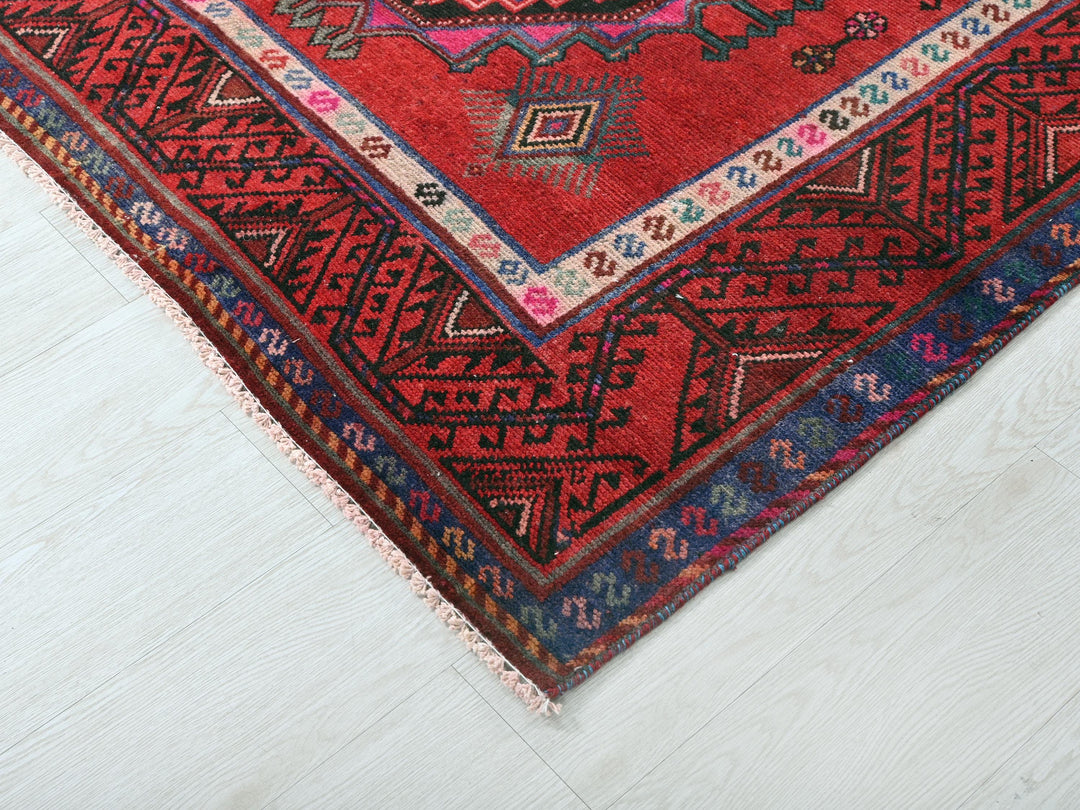 a red oriental rug on a white wooden floor