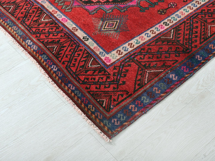 a red oriental rug on a white wooden floor