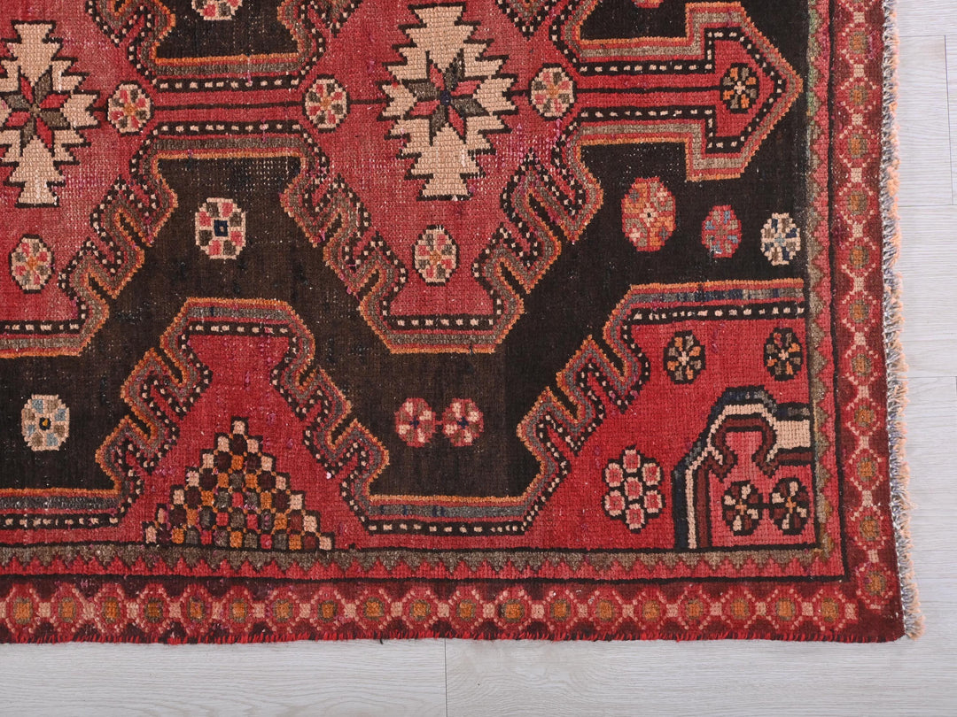 a red and black rug on a wooden floor