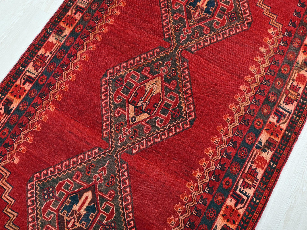 a red oriental rug on a white wooden floor