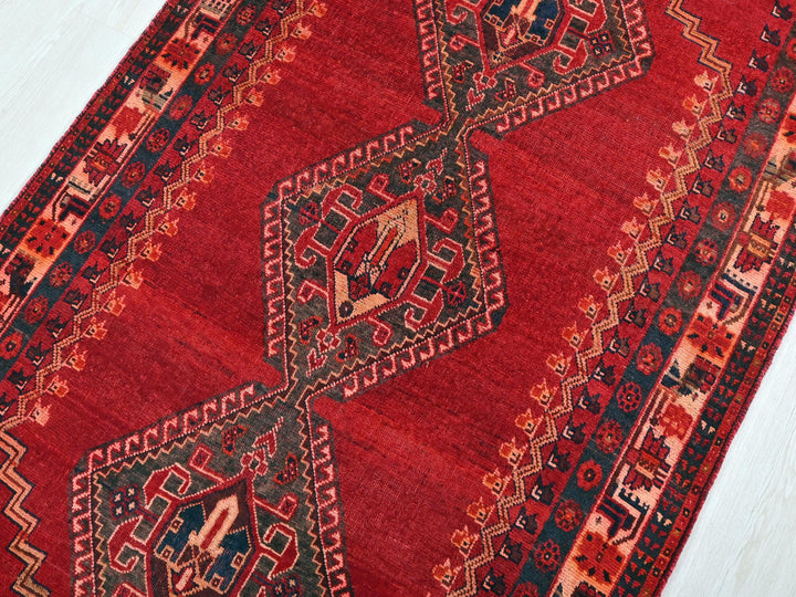 a red oriental rug on a white wooden floor