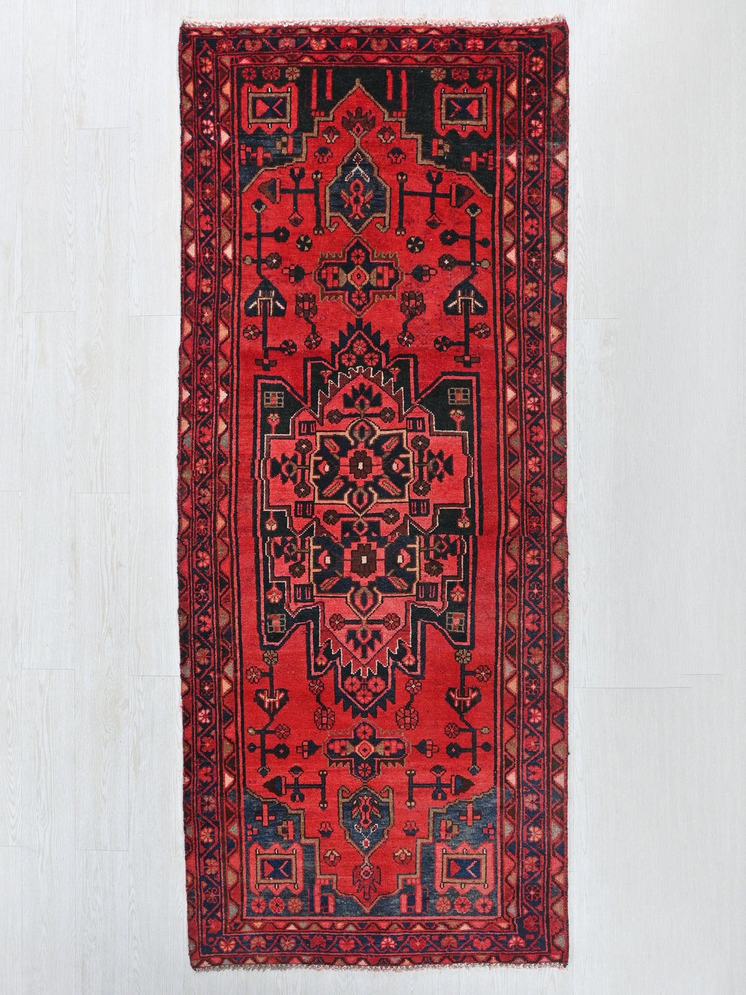 a red rug hanging on a white wall
