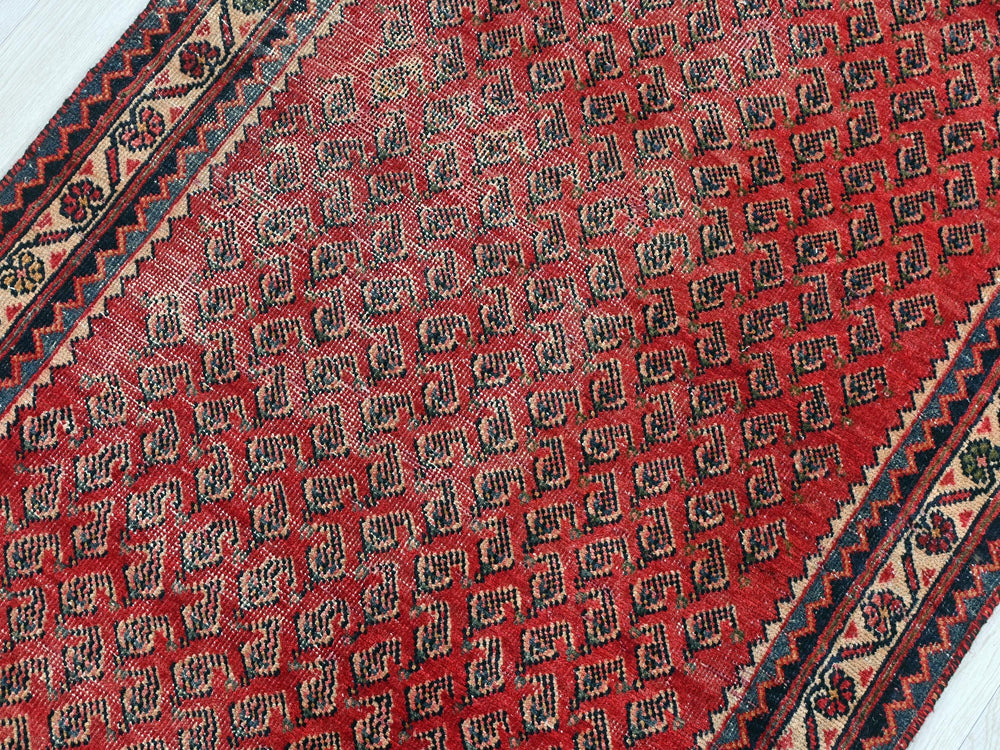 a red and black oriental rug on a wooden floor