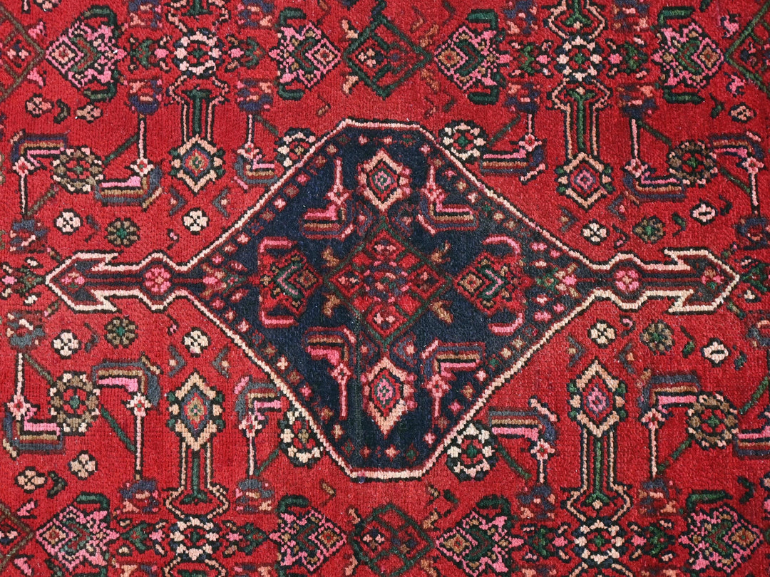 a red rug with a diamond shaped design on it