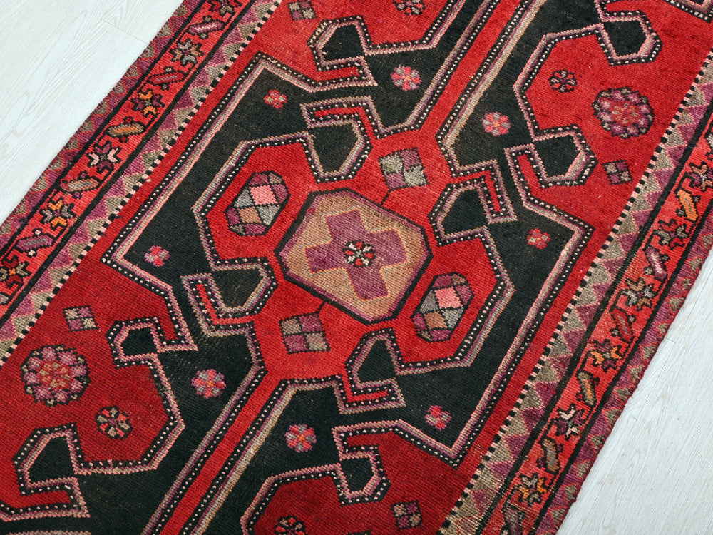 a red and black oriental rug on a white floor