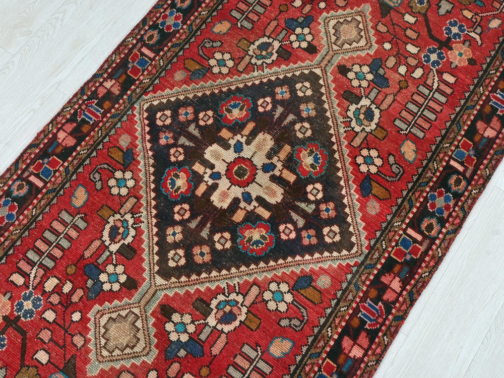 a red oriental rug on a white wooden floor