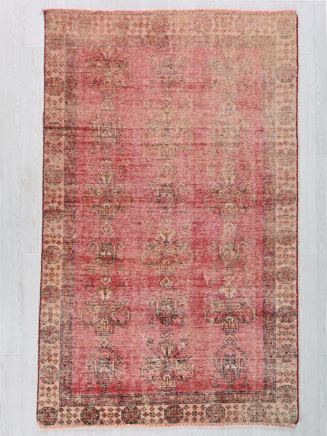a red and beige rug on a wooden floor
