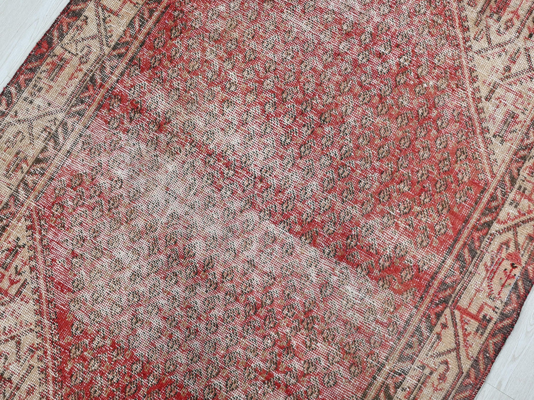 a red and beige oriental rug on a wooden floor