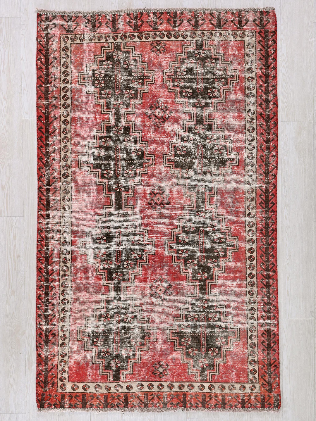 a red and black rug on a white floor
