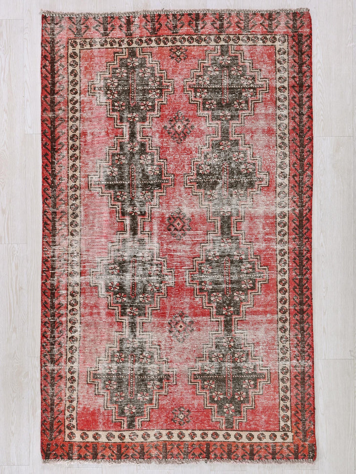 a red and black rug on a white floor