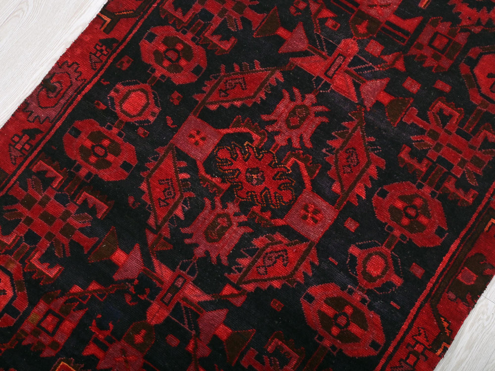 a red and black rug on a white floor