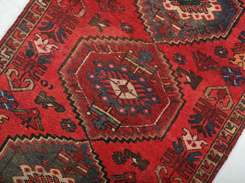 a red oriental rug on a white wooden floor