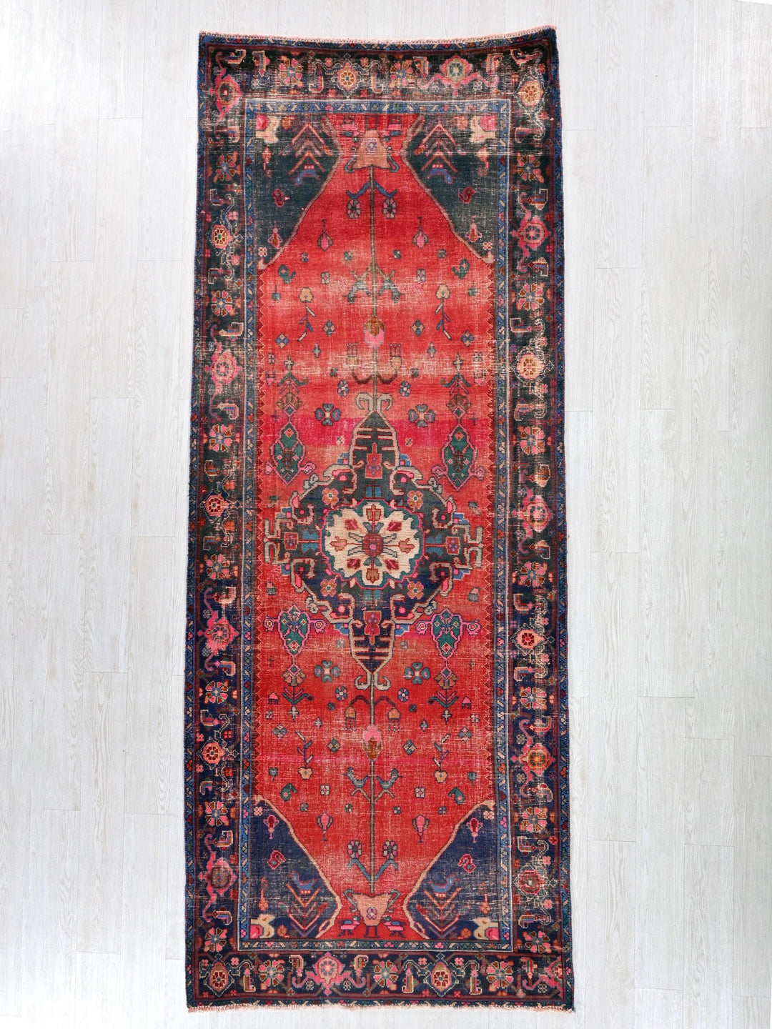 a red rug with a blue border on a white wall