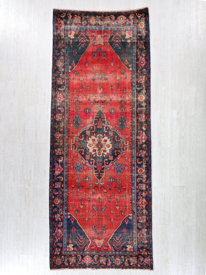 a red rug with a blue border on a white wall