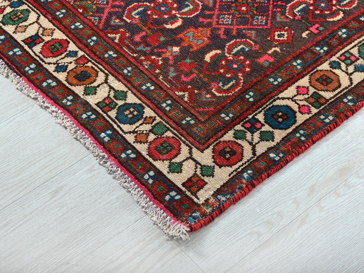 a red rug with a colorful design on a white floor