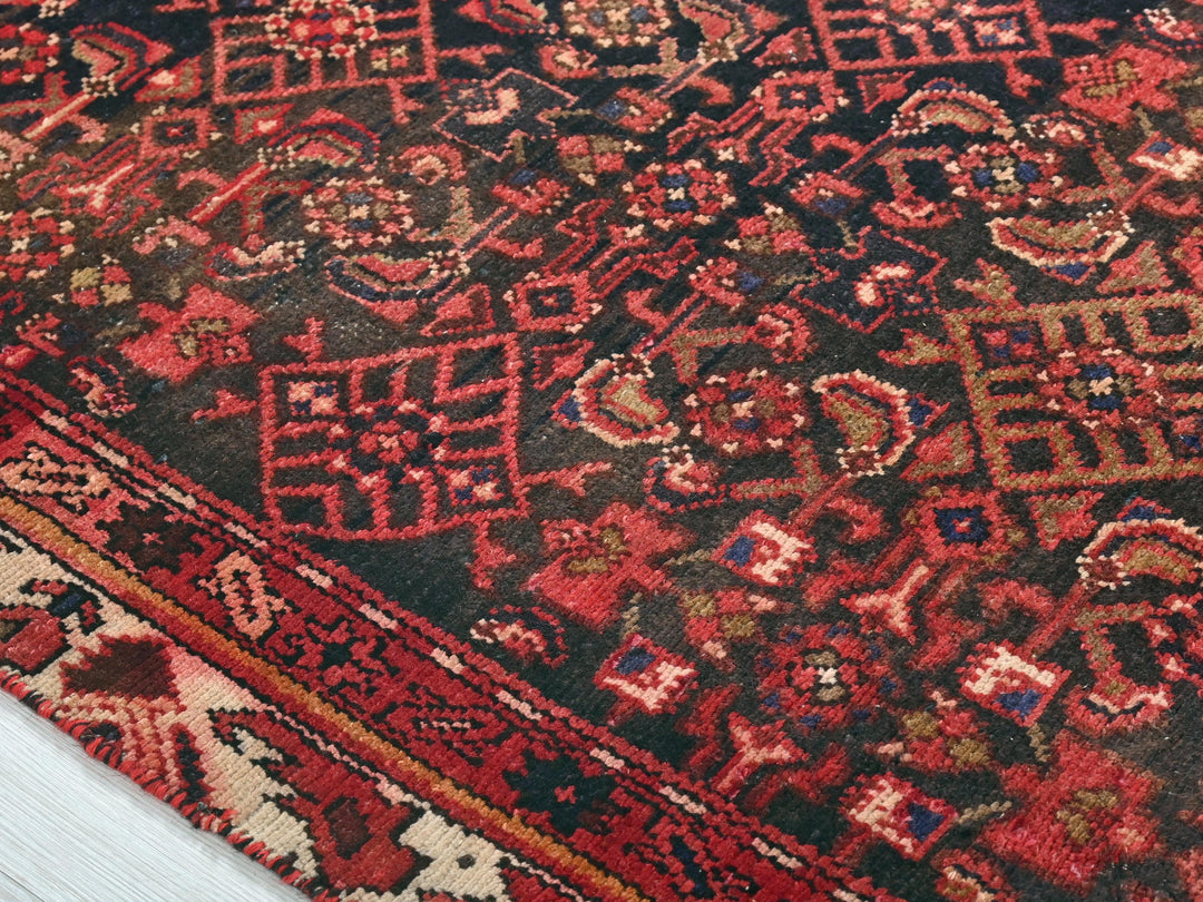 a red and black oriental rug on a wooden floor