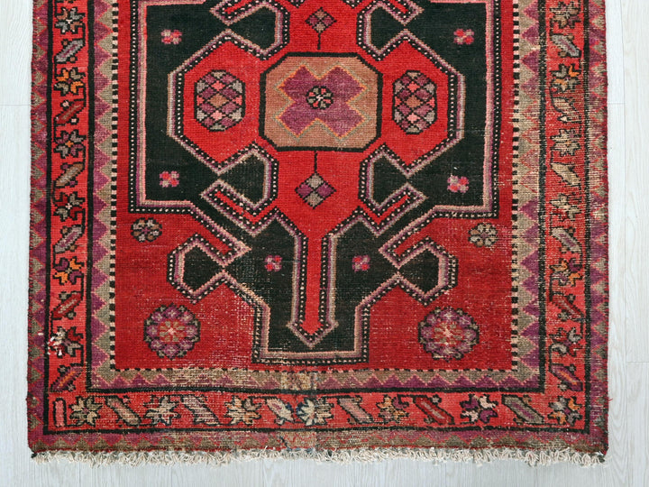 a red and black oriental rug hanging on a wall