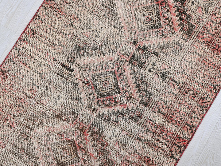 a red and black rug on a wooden floor