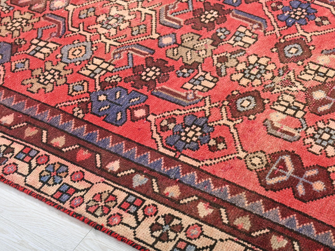 a red oriental rug on a white wooden floor